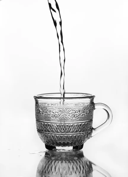 Tasse en verre avec de l'eau versant — Photo