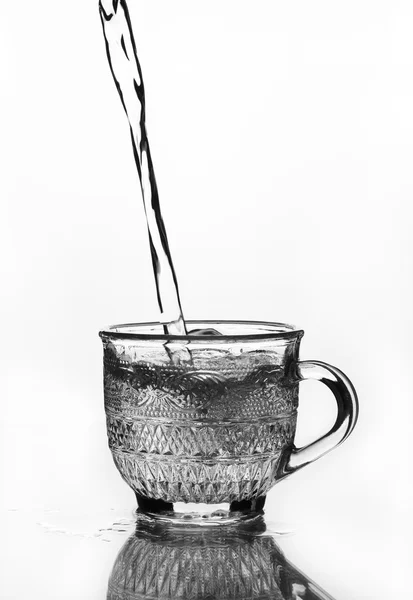 Taza de vidrio con agua vertiendo — Foto de Stock