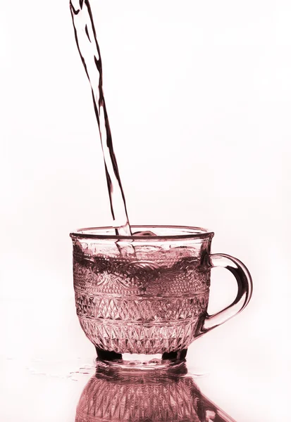 Tazza di vetro con acqua versando — Foto Stock