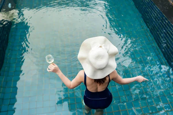 若い女性はプールでリラックスしてワインを飲み — ストック写真