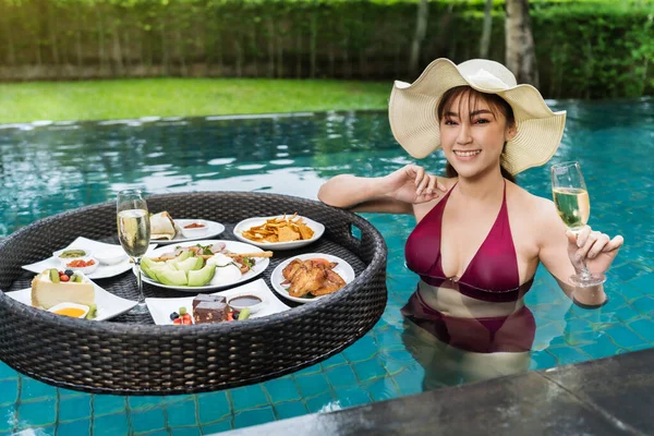 プールで浮遊食品やシャンパングラスで楽しむ陽気な若い女性 — ストック写真