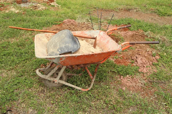 Velho carrinho de mão com areia e equipamento — Fotografia de Stock
