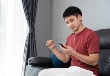 Coronavirus (covid-19) kullanan bir adam evde pamuk burun çubuğu ile hızlı antijen test kiti (atk) kullanıyor.