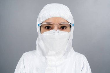 Koruyucu PPE giysili kadın doktor yüz maskesi takıyor ve koronavirüsten (covid-19) korunuyor.