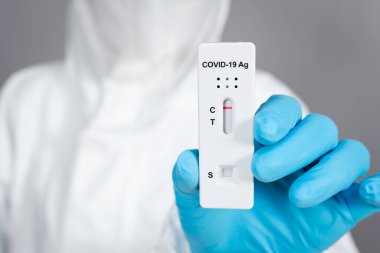 Koronavirüs (Covid-19) taşıyan PPE kıyafetli doktor Antijen Rapid Test kiti (ATK)