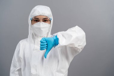 Koruyucu PPE takım elbiseli doktor el işaretini düşürüyor.