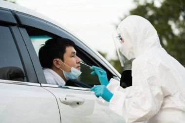PPE giysi test koronavirüsü (covid-19) doktorundan, burun pamuğuyla arabada adama, hızlı test sürüşü yapın
