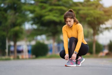 Koşu ayakkabılarını parkta bağlayan kadın.