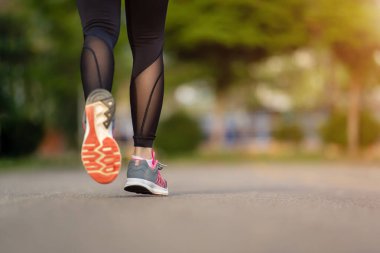 Kapalı kadın ayakları parkta yolda koşuyor.