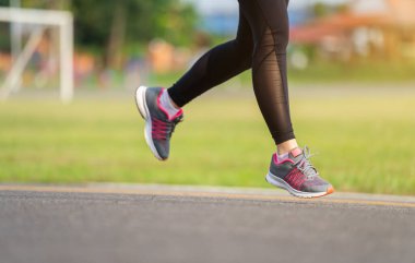 Kapalı kadın ayakları parkta yolda koşuyor.