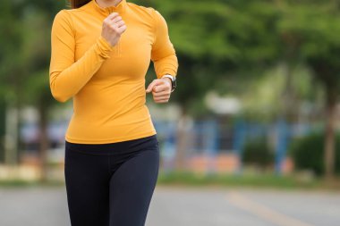 Genç bayan sabahın erken saatlerinde parkta koşuyor.