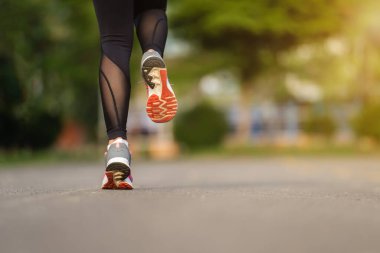 Kapalı kadın ayakları parkta yolda koşuyor.