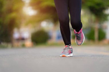 Kapalı kadın ayakları parkta yolda koşuyor.