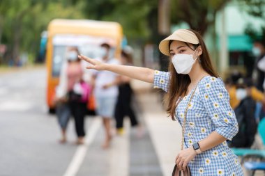 Coronavirus 'u korumak için tıbbi maskeli kadın (covid-19) otobüs durağında otobüs beklerken
