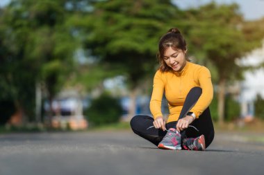 Koşu ayakkabılarını parkta bağlayan kadın.