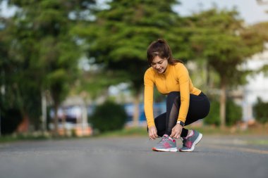 Koşu ayakkabılarını parkta bağlayan kadın.
