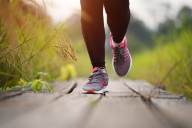 closeup woman feet running on wooden path in field