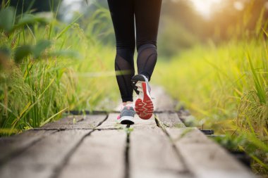 closeup woman feet running on wooden path in field