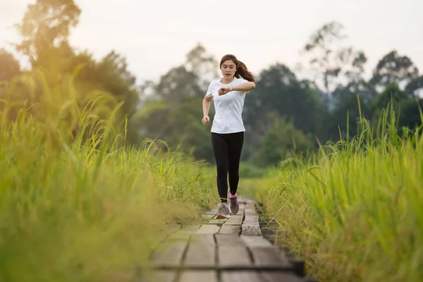 Young Woman Running Looking Her Smart Wrist Watch Wooden Path — Photo