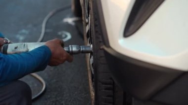 mechanic man using an electric drill to tightening the bolts of vehicle wheel for install a new car tire