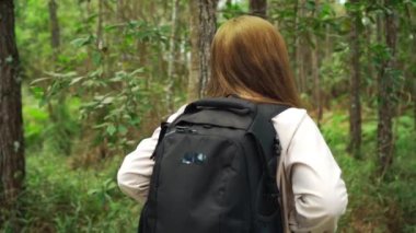 Sırt çantası taşıyan genç bir kadının ormanda ağır çekimde dolaşması.