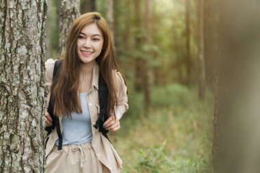 Sırt çantası taşıyan genç ve mutlu bir kadın ormanda seyahat ediyor.