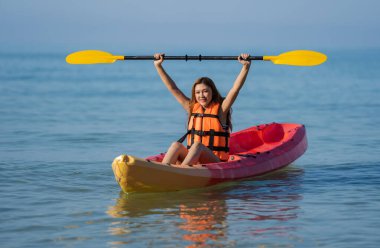 woman in life jacket paddling a kayak boat in the sea clipart
