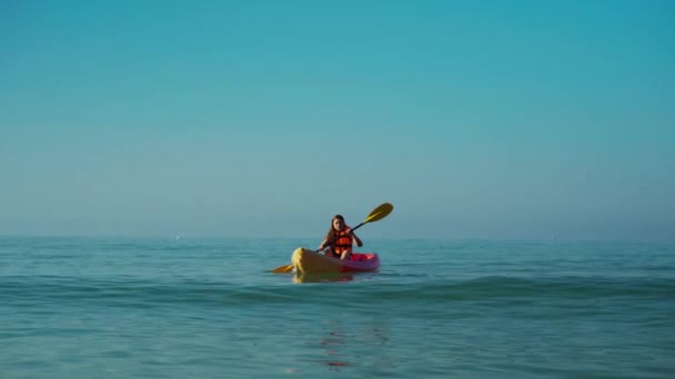 ライフジャケットの女性が海にカヤックボートを漕いでいて — ストック動画