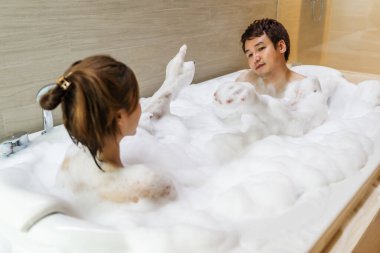 Küvette köpükle yıkanan genç bir çift.