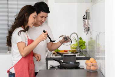 Mutlu genç çift evdeki mutfakta yemek pişiriyor ve yemek hazırlıyor.