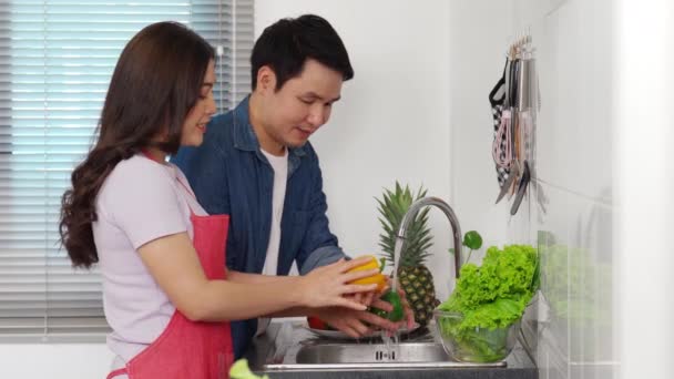 Ευτυχισμένο Νεαρό Ζευγάρι Που Πλένει Λαχανικά Στο Νεροχύτη Της Κουζίνας — Αρχείο Βίντεο