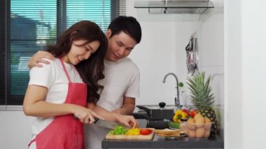 Genç çift evdeki mutfakta sağlıklı yemek hazırlamak için sebze kesiyor.