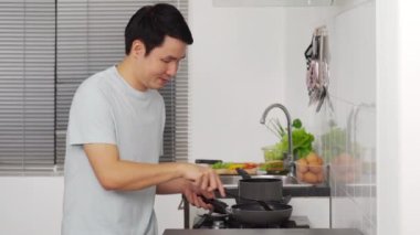 Genç adam evdeki mutfakta yemek pişiriyor ve yemek hazırlıyor.