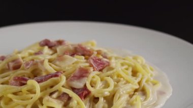 Beyaz tabakta kremalı carbonara spagettisi, döner atış.