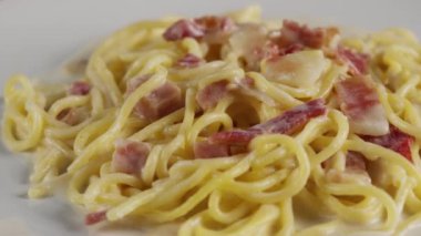 Beyaz tabakta kremalı carbonara spagettisi, döner atış.