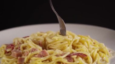 Çatalın yavaş çekimde dönen makarna beyaz bir tabakta döner.