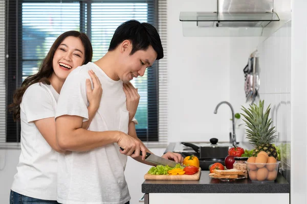 부엌에서 요리할 야채를 준비하는 여자가 남자를 껴안고 — 스톡 사진