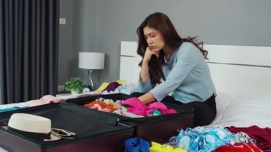 Stresli bir kadın evdeki bir yatakta bavula kıyafet koymakta sorun yaşıyor. Tatil seyahati kavramı.