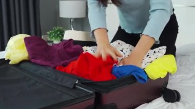 Bir kadının evdeki bir yatakta bavula kıyafet koyması sorun yaratıyor. Tatil seyahati kavramı.