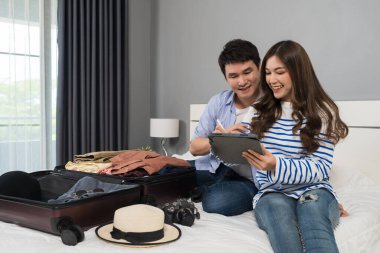 Çift tablet yazıp bavullarını bavula koyuyor evdeki bir yatakta tatil planlıyorlar..