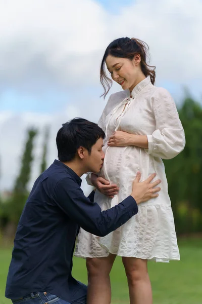 这对已婚夫妇在等着孩子 男人在公园里亲吻他怀孕妻子的腹部 — 图库照片