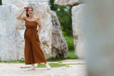 Mutlu hamile kadın parkta dikiliyor.