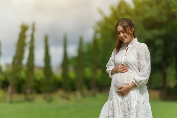 Junge Schöne Schwangere Frau Sucht Und Streichelt Ihren Bauch Park — Stockfoto