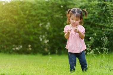 Arazide çimen açan neşeli küçük kız.