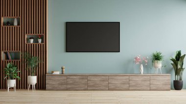 Modern oturma odasındaki mavi duvarda televizyon. Mobilya ve saksı döşeli.
