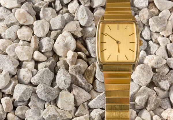 Valse gouden horloge op de gravel — Stockfoto