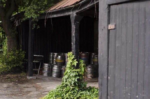 A cache of metal beer barrels in a pub porch