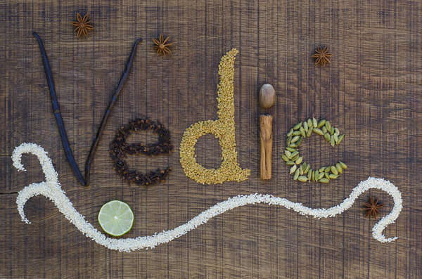 The word Vedic spelled out in ayurveda spices and seeds on a wooden board