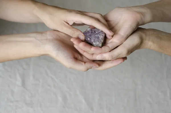 Dames handen geven een Amethist kristal een naar de andere — Stockfoto