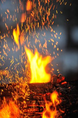 Alevler ve kıvılcımlarla kamp ateşine yakın çekim.